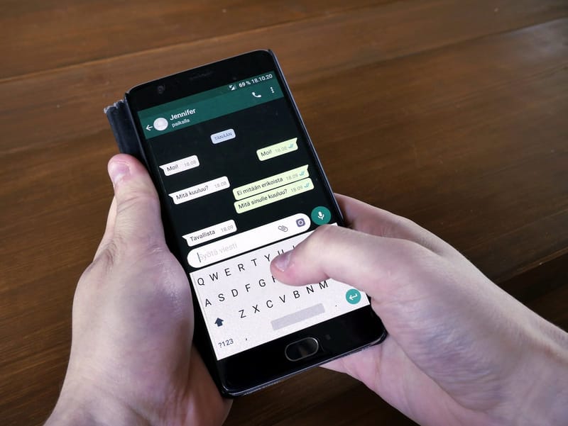 Mãos digitando uma mensagem em uma conversa do WhatsApp em um smartphone